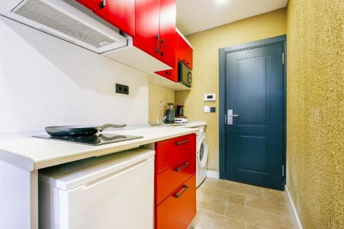 a small kitchen with red cabinets and a blue door at Modern Suite w King Bed 20 min to Hagia Sophia in Istanbul