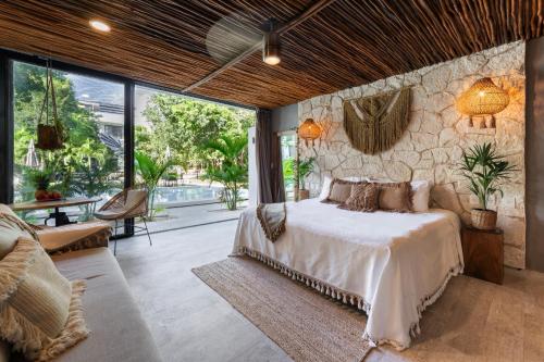 a bedroom with a bed and a stone wall at Luz de Luna Tulum Suite I in Tulum