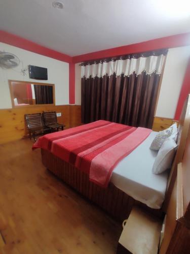 a bedroom with a bed with a red blanket on it at Shyam Cottage, Manali-With Kitchen in Manāli