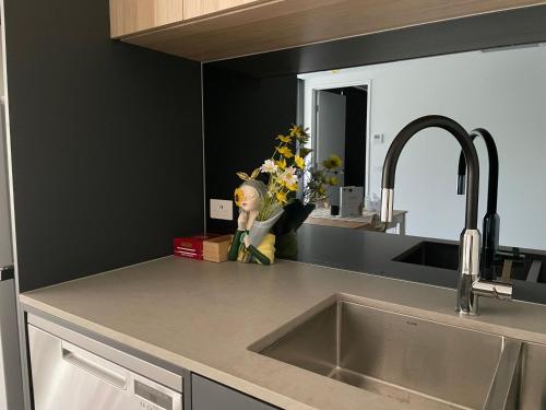 a kitchen counter with a sink and a vase of flowers at New modern 1BR apt near Dickson in Canberra