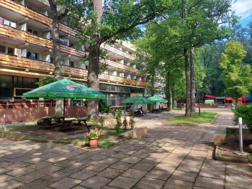 Ośrodek Wypoczynkowo-Hotelowy PRZĄŚNICZKA في لودز: فناء به طاولات ومظلات أمام المبنى