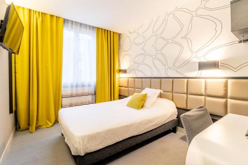 a hotel room with a bed and yellow curtains at Hôtel Astoria in Nantes