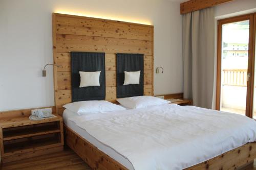 Schlafzimmer mit einem großen Bett mit einem Kopfteil aus Holz in der Unterkunft Hotel Argentum by Bergkristall in Innerpflersch