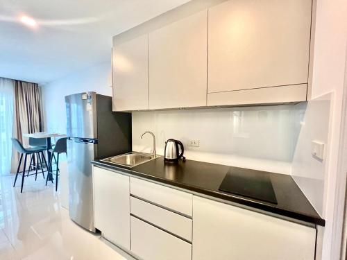 a kitchen with white cabinets and a stainless steel refrigerator at Mantra Beach Condominium Suite - Mae Phim in Ban Tha Fat