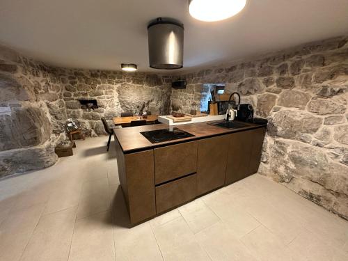 - une cuisine avec des murs en pierre et un comptoir avec un évier dans l'établissement Maison Laurel - Exquisitely Renovated Centuries Old Stone Estate With Private Pool, Near Split and Omiš, à Gata