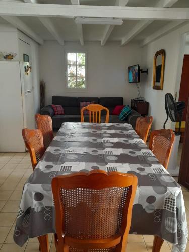 a dining room with a table and chairs and a couch at Maison créole chaleureuse avec stationnement in Le Gosier