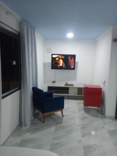 sala de estar con silla azul y TV de pantalla plana en Pousada belo sol en São Pedro da Aldeia