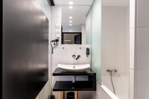 a white bathroom with a sink and a shower at Hôtel Astoria in Nantes