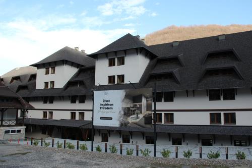 a large white building with a black roof at Kopaonik Apart Bela Reka Brzece in Brzeće