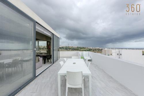 une table et des chaises blanches sur le toit d'un bâtiment dans l'établissement LUX Duplex Penthouse w/ Expansive Rooftop Terrace by 360 Estates, à San Ġwann