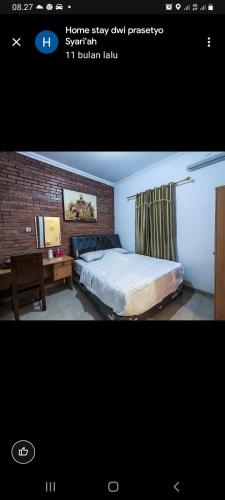 a bedroom with a bed and a desk and a brick wall at Homestay dwi prasetyo in Kembanglimus