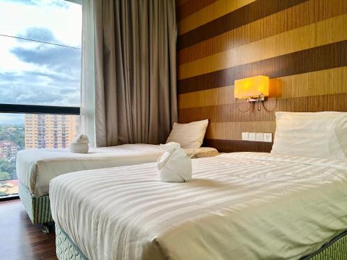 2 Betten in einem Hotelzimmer mit Fenster in der Unterkunft Infini Suites@ D'Majestic Place Kuala Lumpur in Kuala Lumpur
