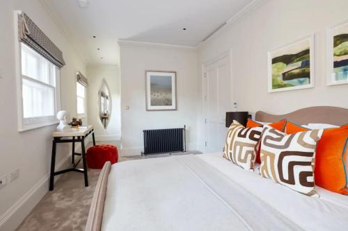 a bedroom with a large bed with orange and white pillows at Modern & Private Belgravia Apartment - Sleeps 4 in London