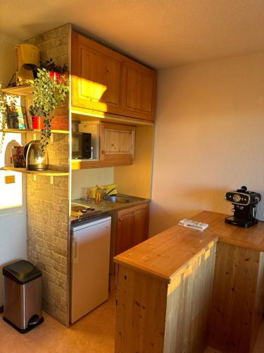 a small kitchen with wooden cabinets and a counter top at Chamrousse - Résidence Le Vernon in Chamrousse