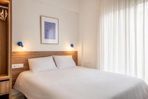 - une chambre avec un lit blanc et une fenêtre dans l'établissement Kallithea Apartments by Olala Homes, à Athènes