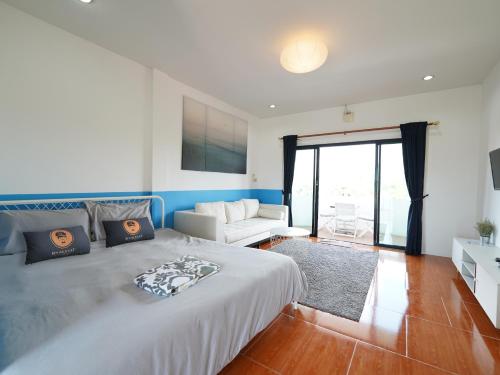 een slaapkamer met een groot bed en een bank bij RoomQuest One Bangsaray in Bang Sare