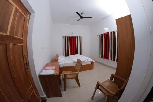 um pequeno quarto com uma cama, uma secretária e uma cadeira. em Ammu's home stay em Panamaram