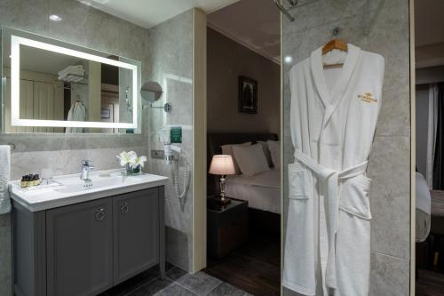 a bathroom with a sink and a shower with a robe at Windsor Hotel & Convention Center Istanbul in Istanbul