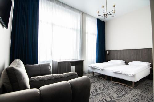 a bedroom with a bed and a couch and a bed and window at AN Hotel in Šiauliai