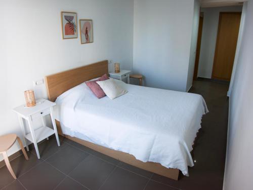 a bedroom with a large white bed and a table at Habitaciones privadas con baño en piso céntrico Gandía in Gandía