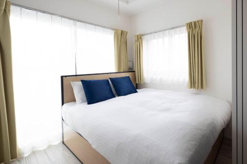 a bedroom with a large white bed with blue pillows at Renaissance Court Jiyugaoka in Tokyo