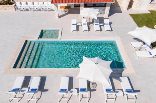 una vista sul soffitto di una piscina con sedie e ombrelloni di Anna Mare Luxury Apartments ad Áfitos