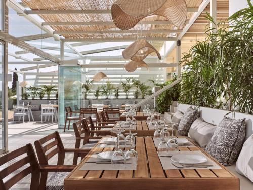 un restaurante con mesas de madera, sillas y plantas en Hotel St John Villas, en Tsilivi