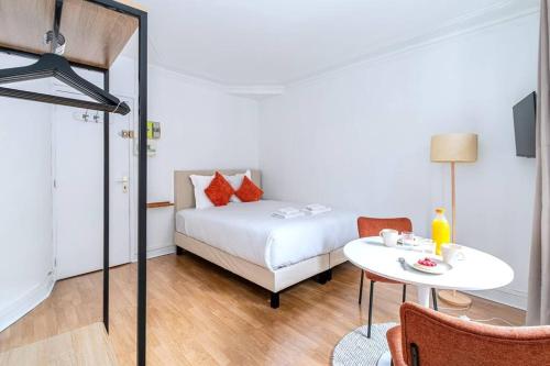 une chambre avec un lit, une table et des chaises dans l'établissement Studio Avenue Philippe Auguste, à Paris