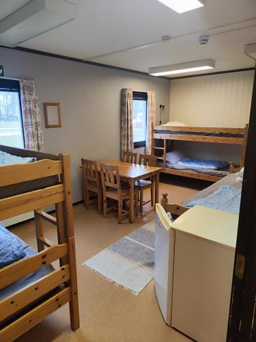 a room with bunk beds and a table and chairs at Bromölla Camping o Vandrarhem in Bromölla