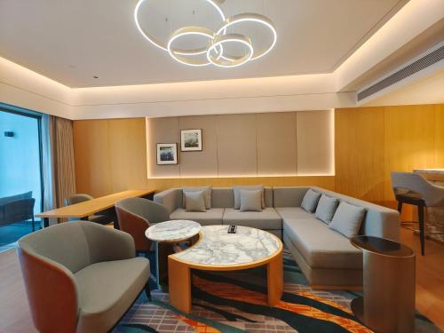 a living room with a couch and tables and a chandelier at Wyndham Grand Zhaoqing Downtown in Zhaoqing