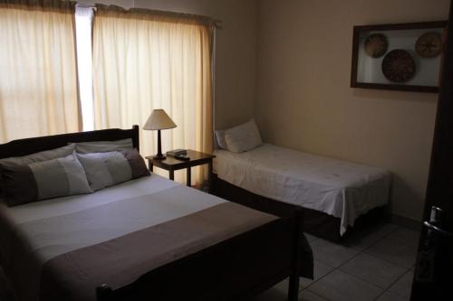 a hotel room with two beds and a window at Apollo Guest House in Mahikeng