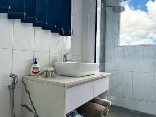 a white bathroom with a sink and a window at SBs Apartment in Suva