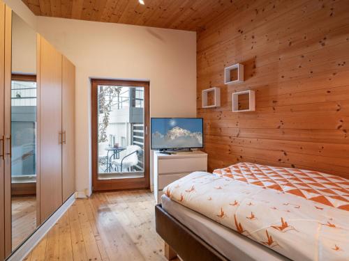 a bedroom with wooden walls and a bed and a television at Appartement Musik-Neureiter in Söll
