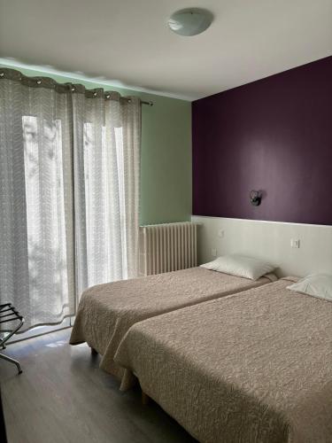 een slaapkamer met twee bedden en een groot raam bij Hotel les Troenes in Montpellier