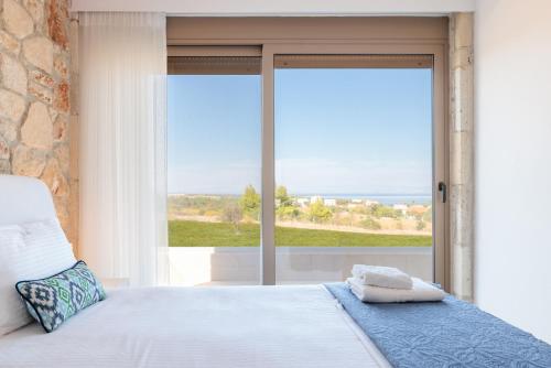 una camera con un letto e una grande finestra di Anna Mare Luxury Apartments ad Áfitos