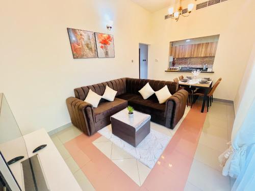 sala de estar con sofá marrón y mesa en Cozy 1 Bedroom apartment in Dubai by Al Ghaimah Holiday Homes, en Dubái