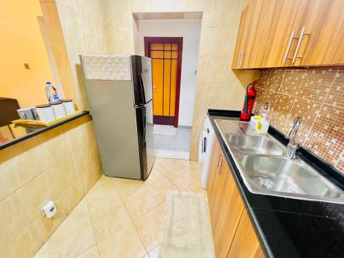 una pequeña cocina con nevera y fregadero en Cozy 1 Bedroom apartment in Dubai by Al Ghaimah Holiday Homes, en Dubái