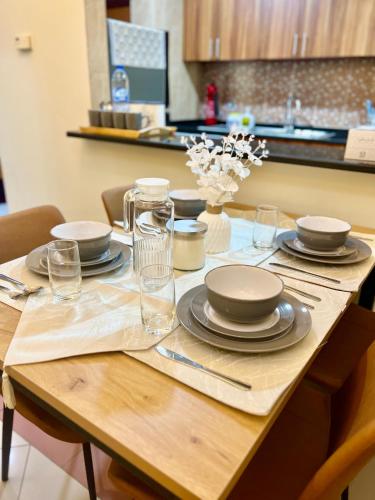a wooden table with plates and glasses on it at Cozy 1 Bedroom apartment in Dubai by Al Ghaimah Holiday Homes in Dubai