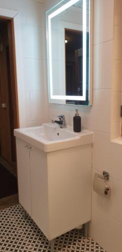 a white bathroom with a sink and a mirror at Tihase studio apartment with sauna in Tallinn