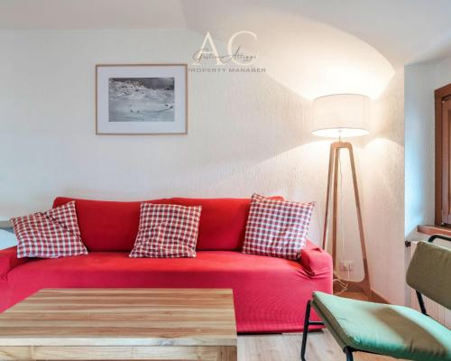 a red couch in a living room with a lamp at Square Apartment in Ponte di Legno
