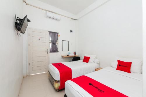 two beds in a room with red and white at RedDoorz Syariah near RSUD Zainoel Abidin Banda Aceh in Banda Aceh