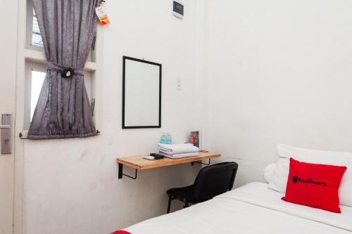 a bedroom with a desk and a bed and a chair at RedDoorz Syariah near RSUD Zainoel Abidin Banda Aceh in Banda Aceh