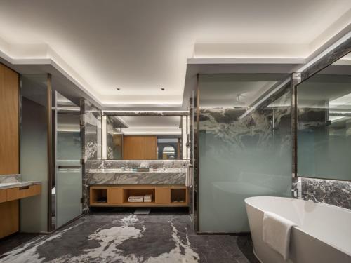 a bathroom with a tub and a large mirror at Wyndham Grand Zhaoqing Downtown in Zhaoqing