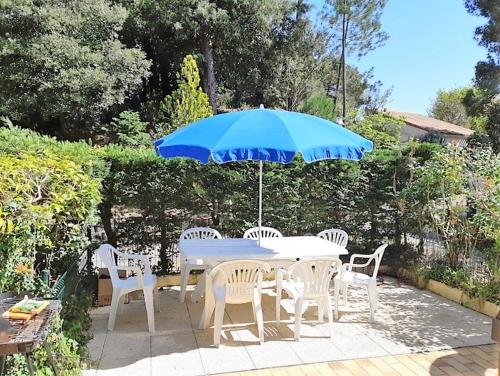 une table et des chaises avec un parapluie bleu dans l'établissement La Palmyre - CHALEUREUSE MAISON MITOYENNE - PROXIMITE CENTRE, aux Mathes