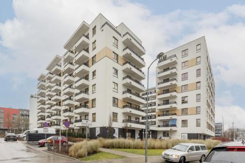 un grand immeuble blanc avec des voitures garées dans un parking dans l'établissement Business Apartment Mokotów by Noclegi Renters, à Varsovie