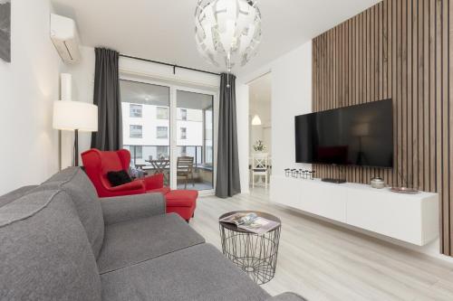 華沙的住宿－Business Apartments Mokotów by Renters，客厅配有灰色的沙发和红色的椅子