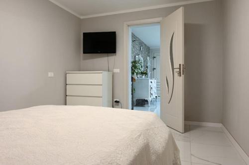 een witte slaapkamer met een bed en een televisie bij Piazzola holiday home * * * * * 