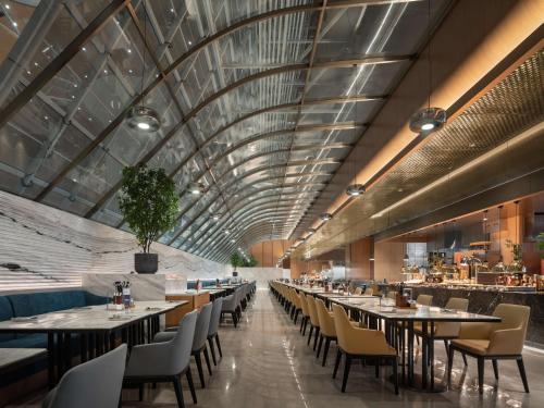 a restaurant with tables and chairs and a ceiling at Wyndham Grand Zhaoqing Downtown in Zhaoqing