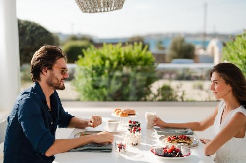 a man and woman sitting at a table eating food at White Dunes Luxury Boutique Hotel in Santa Maria