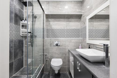 La salle de bains est pourvue de toilettes, d'un lavabo et d'une douche. dans l'établissement One Bedroom Apartment Next To Arbat In The Heart of Almaty, à Almaty